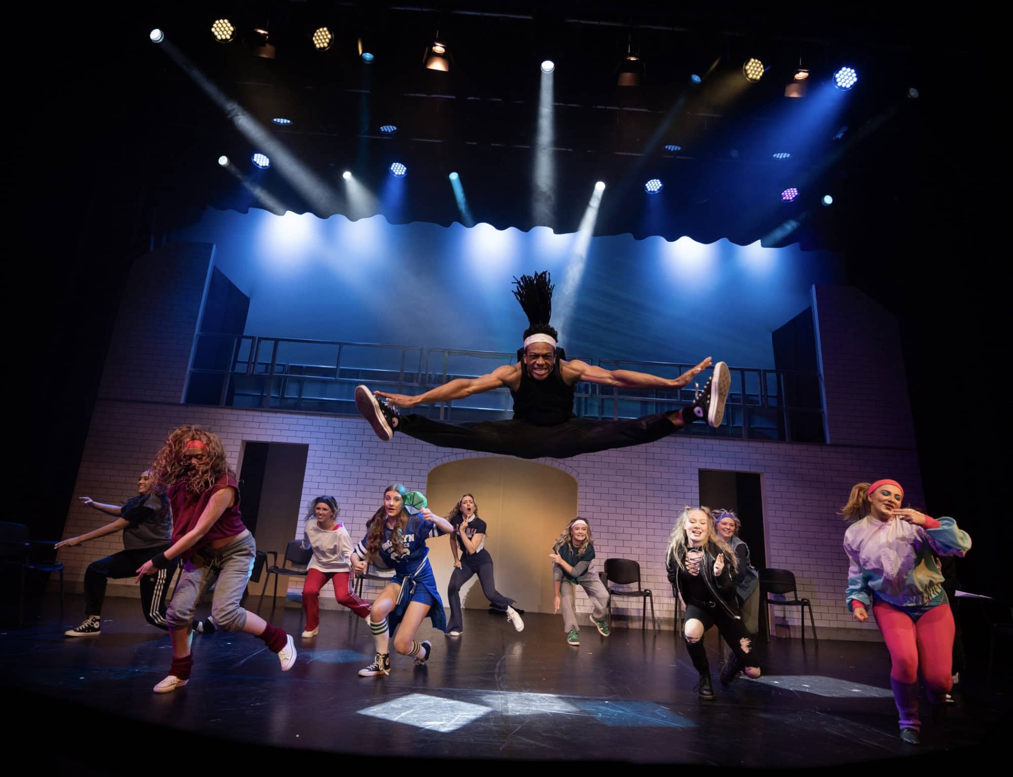 Dynamic dance performance on stage with energetic dancers and vibrant lighting.